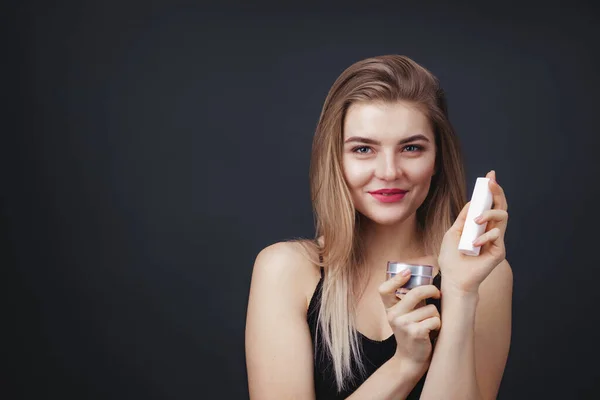 Mooie vrouw met natuurlijke make-up houden potten van schoonheidsproducten — Stockfoto