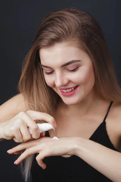 Mujer encantadora con perfecto aspecto saludable aplicando producto para el cuidado de la piel — Foto de Stock