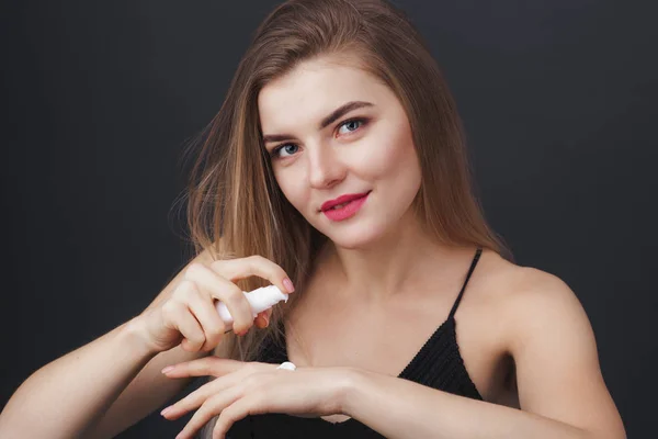 Mujer encantadora con perfecto aspecto saludable aplicando producto para el cuidado de la piel — Foto de Stock