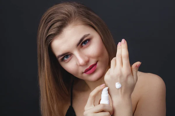 Mujer encantadora con maquillaje natural aplicando producto para el cuidado de la piel — Foto de Stock