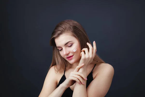 Mooie vrouw met een gladde gezonde huid die crème op haar gezicht aanbrengt — Stockfoto