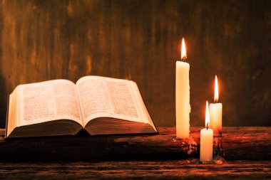 İncil haç ve boncuk eski meşe ahşap bir masa üzerinde bir mum. Güzel altın arka plan. Din kavramı.