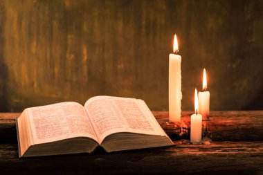 İncil haç ve boncuk eski meşe ahşap bir masa üzerinde bir mum. Güzel altın arka plan. Din kavramı.