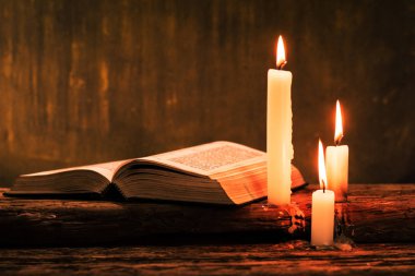 İncil haç ve boncuk eski meşe ahşap bir masa üzerinde bir mum. Güzel altın arka plan. Din kavramı.