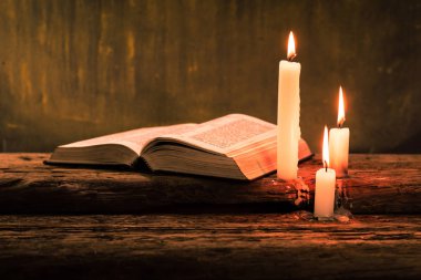 İncil haç ve boncuk eski meşe ahşap bir masa üzerinde bir mum. Güzel altın arka plan. Din kavramı.