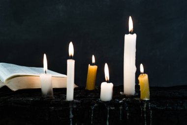 İncil haç ve boncuk bir mum eski ahşap yanmış masa. Güzel arka plan. Din kavramı.