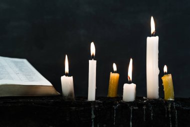 İncil haç ve boncuk bir mum eski ahşap yanmış masa. Güzel arka plan. Din kavramı.