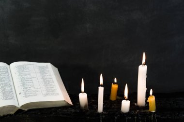 İncil haç ve boncuk bir mum eski ahşap yanmış masa. Güzel arka plan. Din kavramı.
