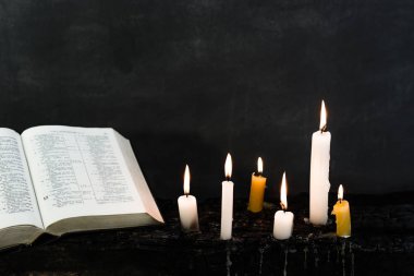 İncil haç ve boncuk bir mum eski ahşap yanmış masa. Güzel arka plan. Din kavramı.