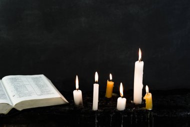 İncil haç ve boncuk bir mum eski ahşap yanmış masa. Güzel arka plan. Din kavramı.