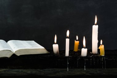 İncil haç ve boncuk bir mum eski ahşap yanmış masa. Güzel arka plan. Din kavramı.