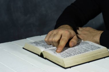 Kutsal İncil okuma bir masada oturan genç adam