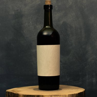Eski bir ahşap masa üzerinde beyaz dokusal etiket ile kırmızı şarap şişesi. Güzel koyu arka plan