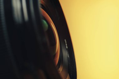 Sarı arka plandaki güzel siyah kamera lensini kapat. Makro görünüm..