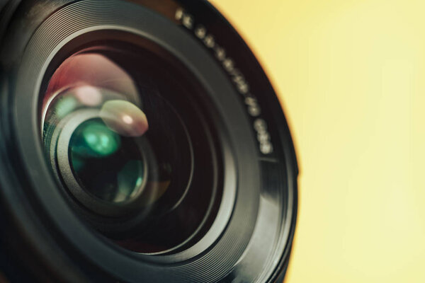 Beautiful camera lens with yellow and pink light of glass on a black background.