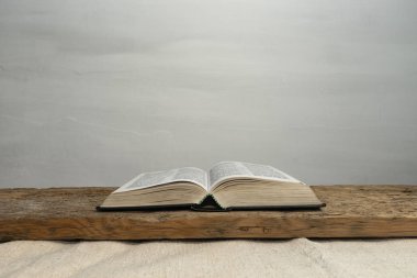 Eski ahşap bir masa ve beyaz duvar arka planında İncil 'i aç. Din kavramı.