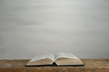 Eski ahşap bir masa ve beyaz duvar arka planında İncil 'i aç. Din kavramı.