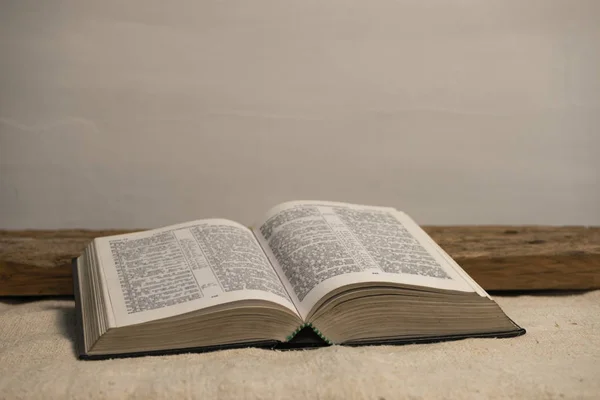 古い木製のテーブルと白い壁の背景に聖書を開きます 宗教概念 — ストック写真