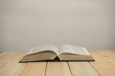 Eski ahşap bir masa ve beyaz duvar arka planında açık İncil. Din kavramı.