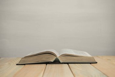 Eski ahşap bir masa ve beyaz duvar arka planında açık İncil. Din kavramı.