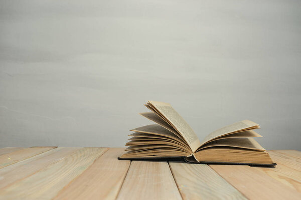 Old Books on a wooden table and white wall background.