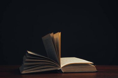 Kırmızı ahşap bir masa üzerinde bir açık eski kitap. Güzel koyu arka plan.