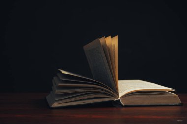 Kırmızı ahşap bir masa üzerinde bir açık eski kitap. Güzel koyu arka plan.