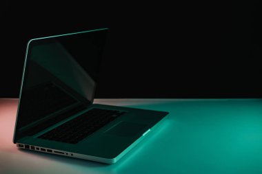 Masa ve gece arkaplanındaki renkli ışıkta güzel gümüş bir laptop..