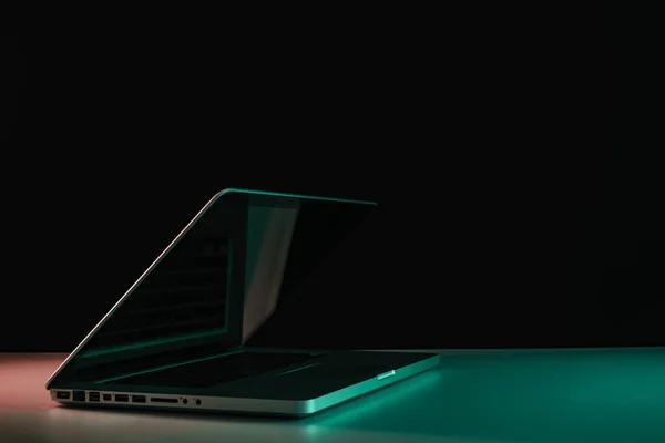 Beautiful silver laptop in the color light on a table and night background.