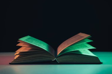 Masa ve gece arkaplanındaki renkli ışıkta güzel, eski bir kitap..