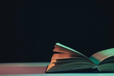 Masa ve gece arkaplanındaki renkli ışıkta güzel, eski bir kitap..