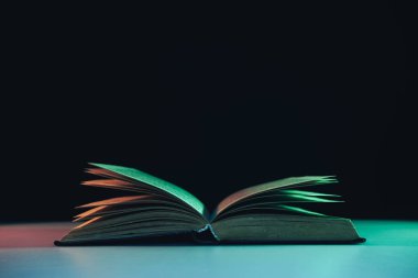 Masa ve gece arkaplanındaki renkli ışıkta güzel, eski bir kitap..