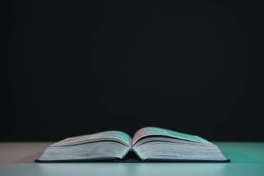 Kırmızı beyaz bir masada açık İncil. Güzel siyah arkaplan.