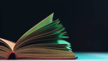 Masa ve gece arkaplanındaki renkli ışıkta güzel kitap sayfalarını kapat.