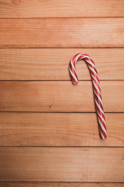 Beautiful striped hard candy cane staff on a wooden table background.