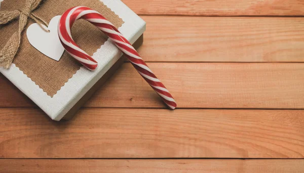 Beautiful striped hard candy cane staff on a wooden table background.