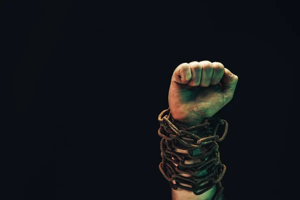 Human hand are chained in chains isolated on black background.