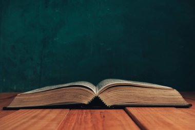 Eski kırmızı ahşap bir masanın üzerine İncil 'i kapat. Güzel yeşil duvar arka planı.