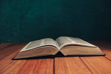 Eski kırmızı ahşap bir masanın üzerine İncil 'i kapat. Güzel yeşil duvar arka planı.