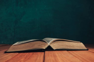 Eski kırmızı ahşap bir masanın üzerine İncil 'i kapat. Güzel yeşil duvar arka planı.