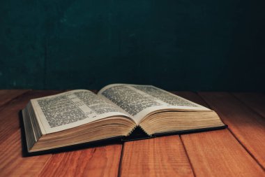 Eski kırmızı ahşap bir masanın üzerine İncil 'i kapat. Güzel yeşil duvar arka planı.