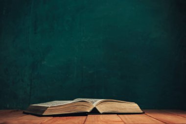 Eski kırmızı ahşap bir masada İncil 'i aç. Güzel yeşil duvar arka planı.