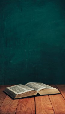 Eski kırmızı ahşap bir masada İncil 'i aç. Güzel yeşil duvar arka planı.