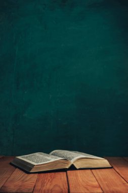 Eski kırmızı ahşap bir masada İncil 'i aç. Güzel yeşil duvar arka planı.