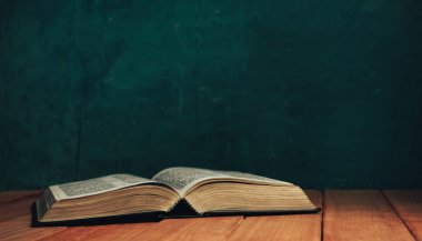 Eski kırmızı ahşap bir masada İncil 'i aç. Güzel yeşil duvar arka planı.