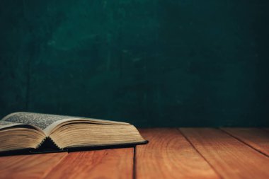 Eski kırmızı ahşap bir masanın üzerine İncil 'i kapat. Güzel yeşil duvar arka planı.