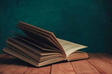 Kırmızı ahşap bir masada eski bir kitap. Yeşil duvarın arkaplanı.
