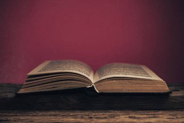 Eski bir meşe ağacından masa ve kırmızı duvarın arkasındaki eski kitabı kapat..