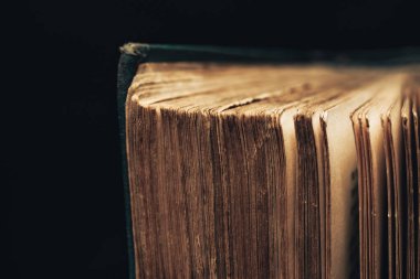 Siyah arka planda çekilen antik kitap çekimlerini kapat. Kitap kötü durumda..