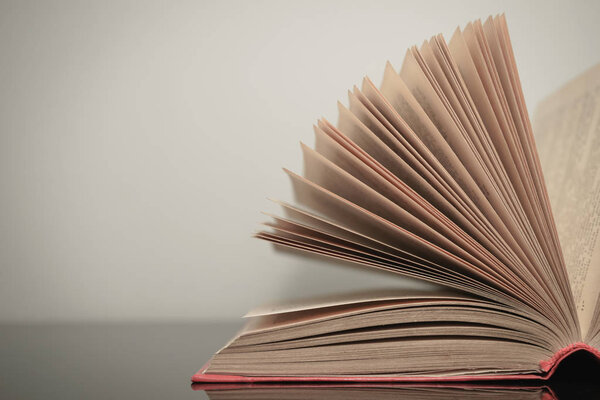 Close up beautiful open book on a gray and glass table background. 